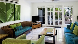 Una sala de estar con un sofá, sillones, una mesa de centro y un televisor.