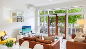 Una sala de estar moderna con un televisor grande, asientos cómodos y ventanas amplias con vistas al exterior.