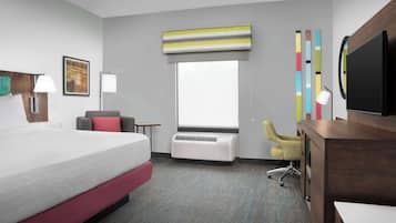 Habitación de hotel con una cama grande, un escritorio, una silla, un televisor, una ventana y un equipo de aire acondicionado.