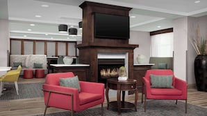 Una sala de estar moderna con chimenea, sillones rojos, una butaca amarilla y un televisor de pantalla plana sobre la chimenea.