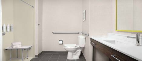 A modern bathroom with a white toilet, a sink with a mirror, and a shower area.