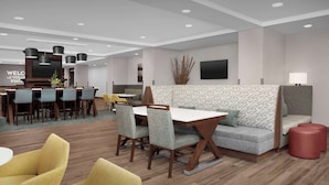 Un moderno vestíbulo de hotel con zona de comedor, asientos y una recepción.