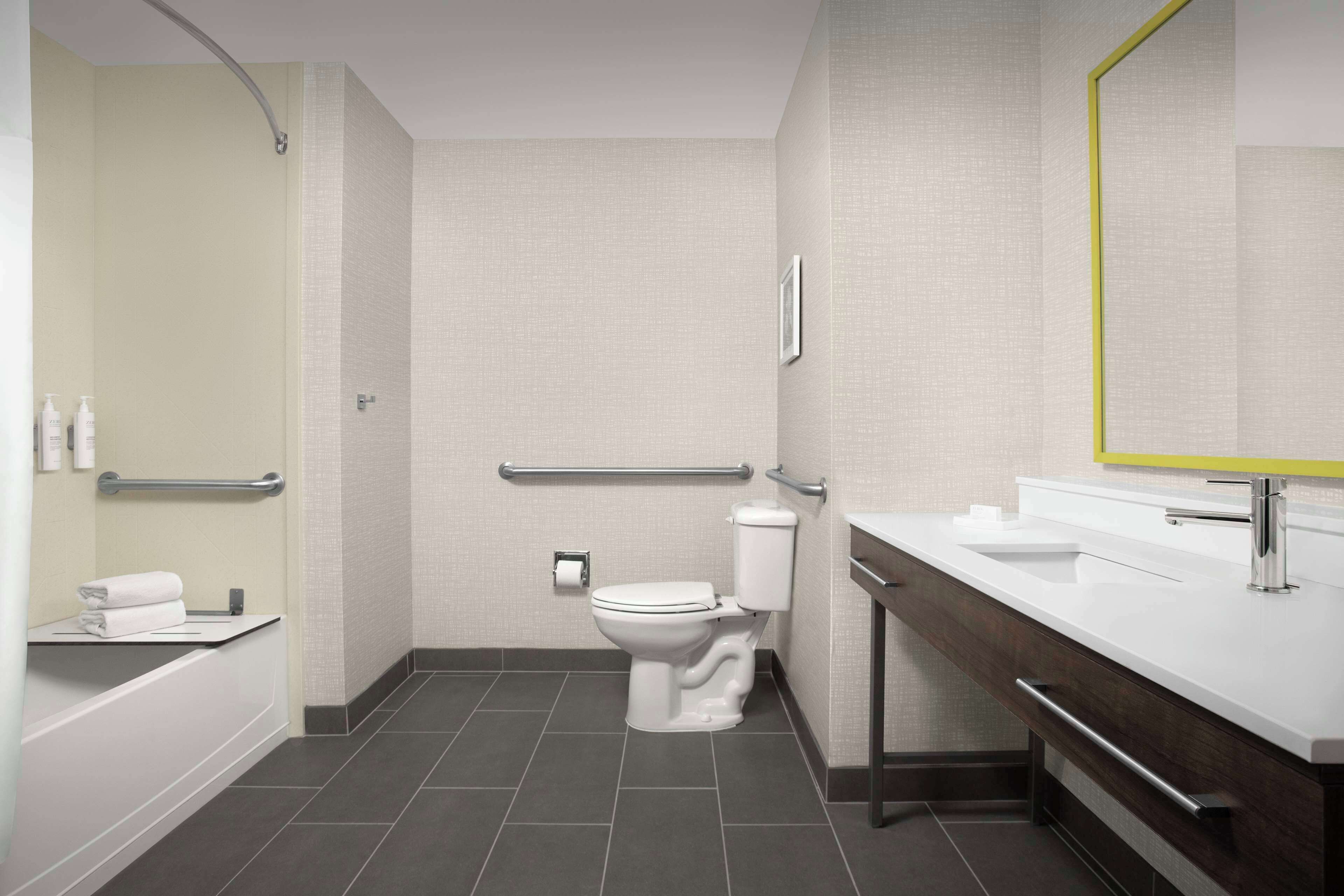 Een moderne badkamer met toilet, bad, wastafel met spiegel en een douche.