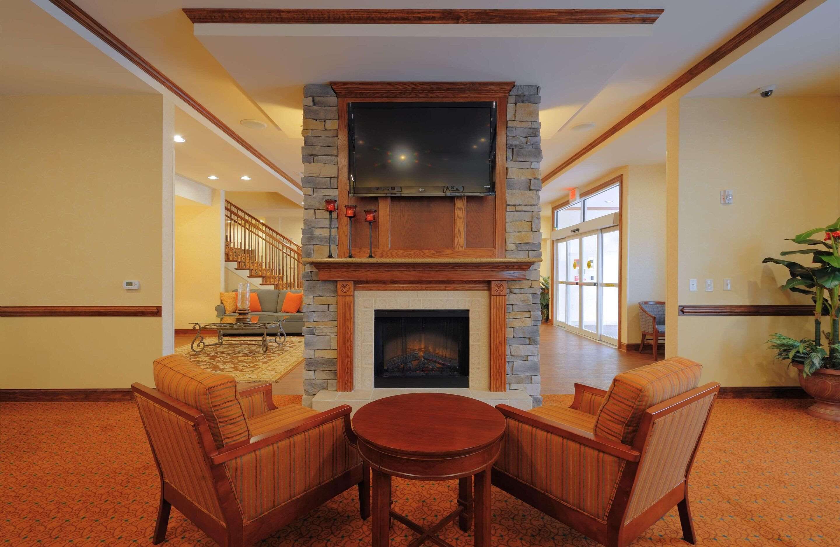 Un hall con chimenea de piedra, un televisor de pantalla plana y una zona de estar con dos sillones y una mesa.