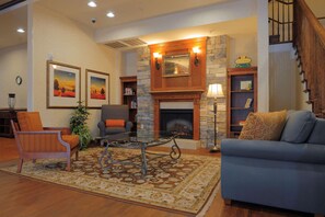 A cozy living room with a fireplace, comfortable seating, and a staircase. - Country Inn & Suites by Radisson, Columbia at Harbison, SC (Columbia)