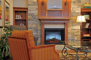 A cozy living room with a fireplace, a bookshelf, and a comfortable armchair.
