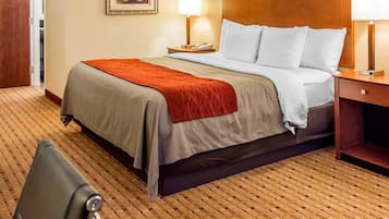 A hotel room with a bed, two bedside lamps, a nightstand, a framed picture on the wall, and a chair.