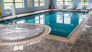Une piscine intérieure avec des panneaux indiquant clairement les règles d’utilisation, un jacuzzi et des chaises longues.