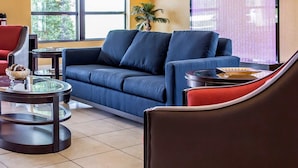 Un salon moderne avec un canapé bleu, un fauteuil rouge et une table basse en verre.