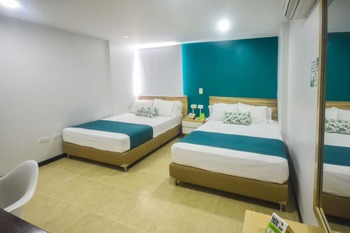 Habitación de hotel con dos camas, un escritorio y una silla.