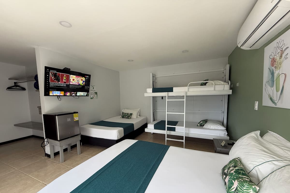 Habitación de hotel con literas, escritorio, televisor y aire acondicionado.