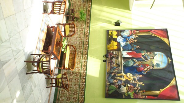 A room with a tiled floor, a green wall, and a large painting depicting a historical scene.