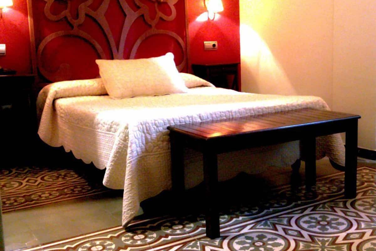 Un dormitorio con cama, mesita de noche y suelo estampado.