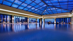 A spacious indoor swimming pool with a glass ceiling, large windows, and sun loungers. - Mels Weldon Dongguan Humen (Dongguan)