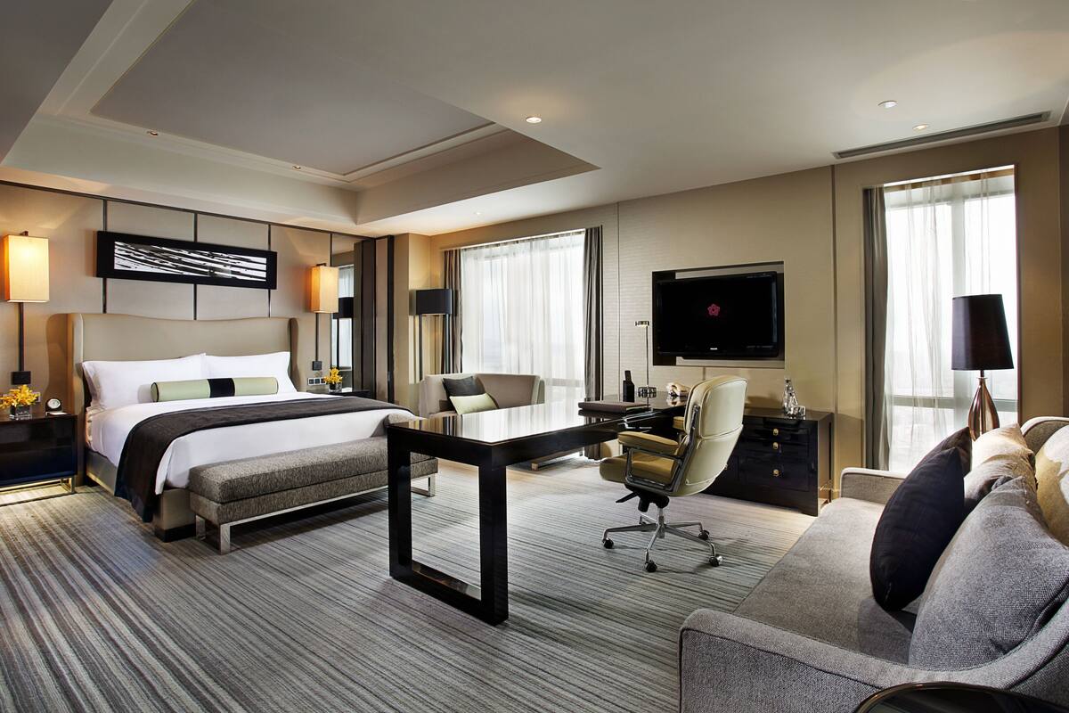 Une chambre d’hôtel moderne équipée d’un grand lit, d’un bureau, d’une chaise et d’un téléviseur.