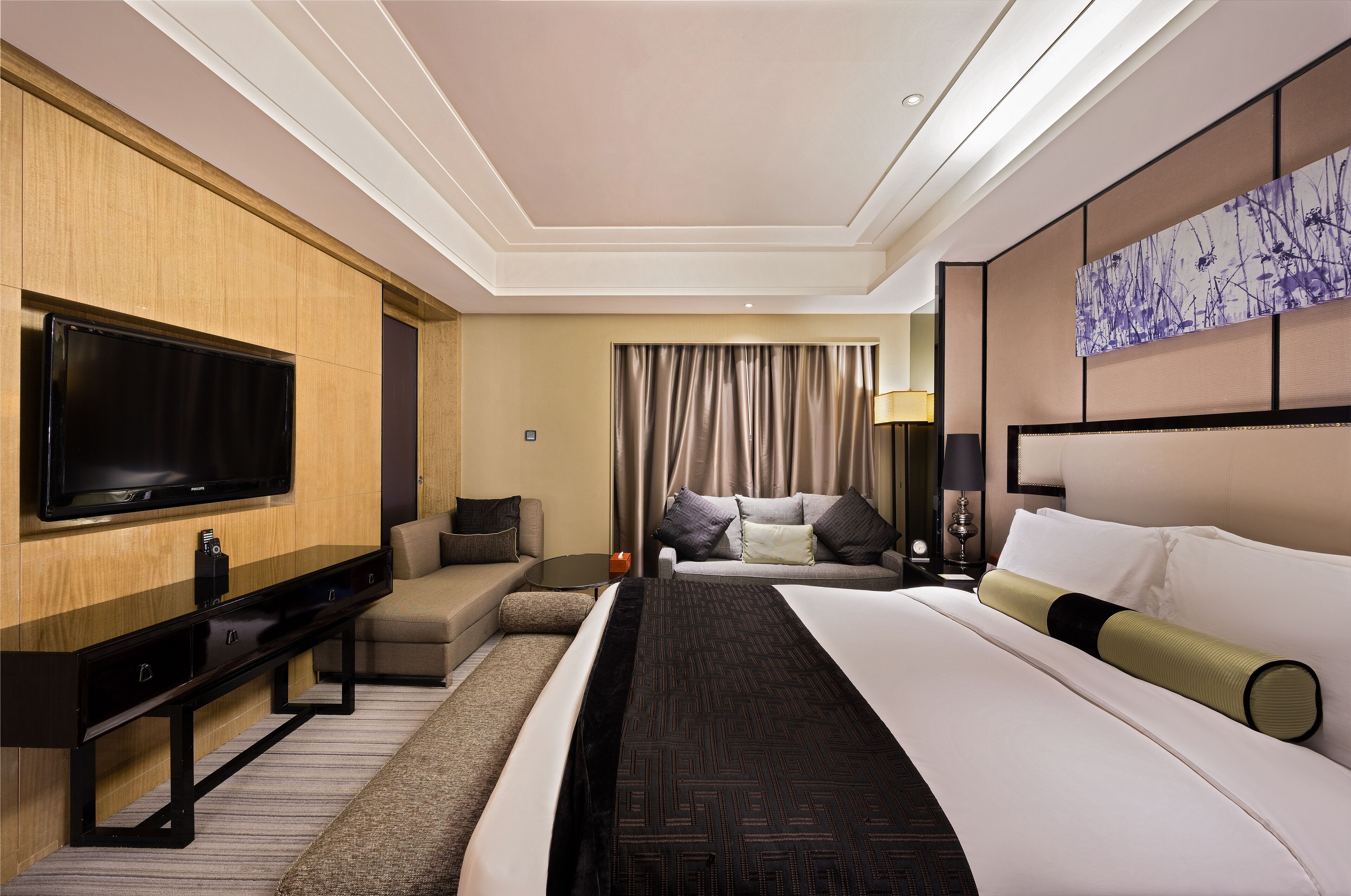 Une chambre d’hôtel équipée d’un téléviseur à écran plat, d’un canapé, d’un lit avec une literie blanche et verte, et d’une grande œuvre d’art accrochée au mur.
