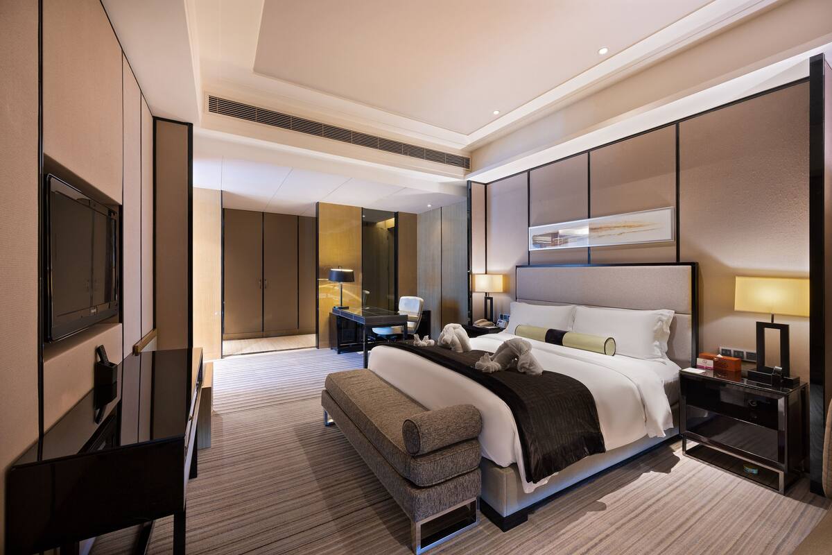 Une chambre d’hôtel moderne équipée d’un grand lit, d’un bureau, d’une chaise et d’un téléviseur.