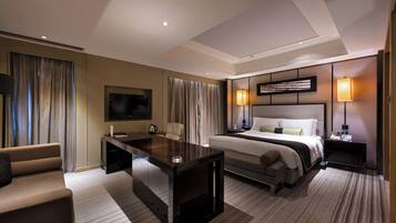 A hotel room with a bed, a desk, a chair, a TV, and a bedside table.