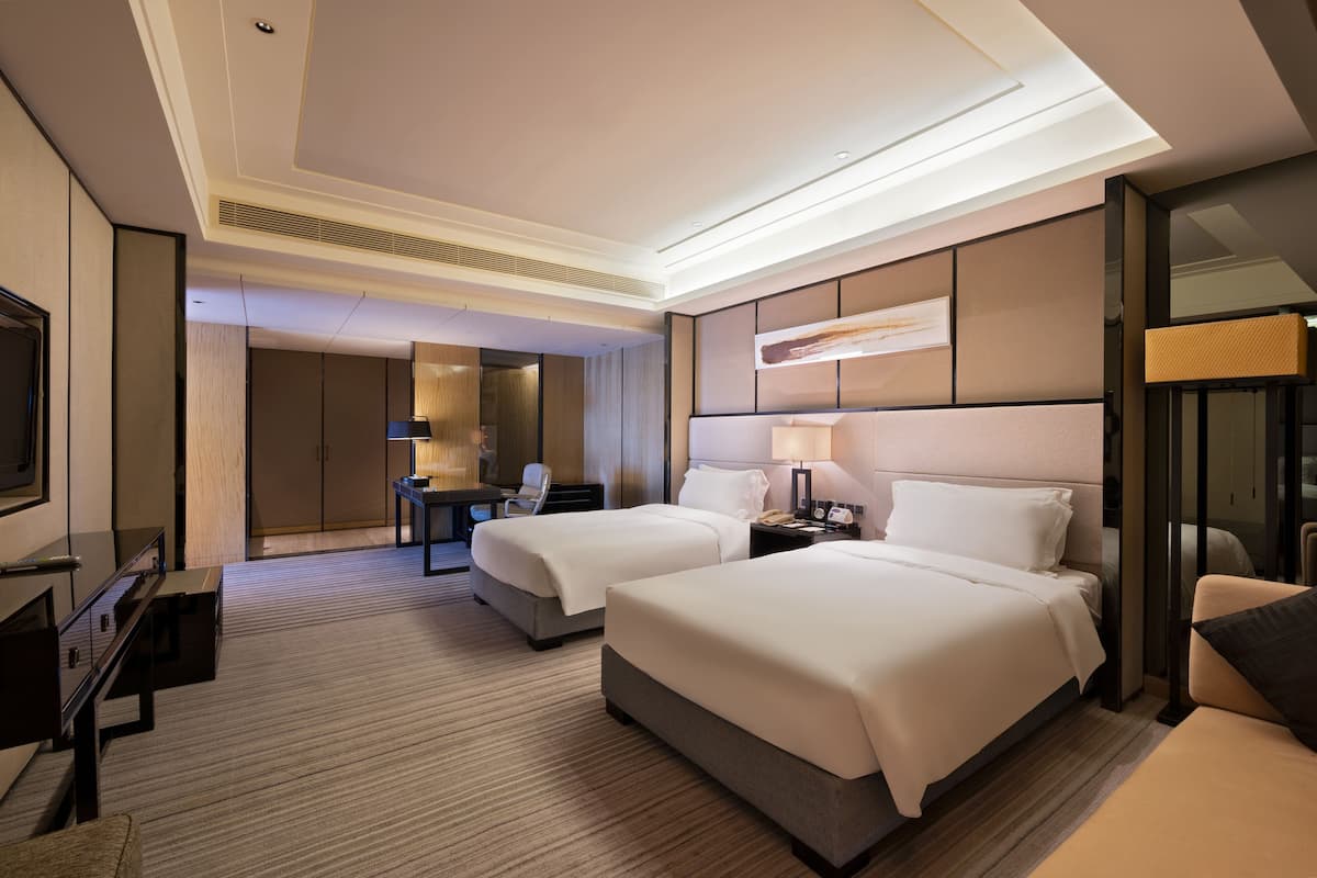 Une chambre d’hôtel avec deux lits, un bureau, une chaise, une télévision et un mini-bar.