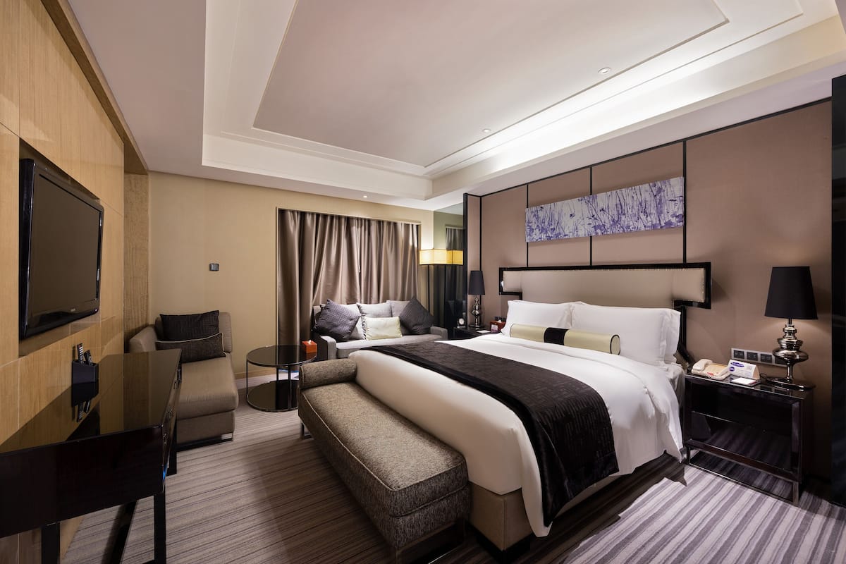 Une chambre d’hôtel moderne dotée d’un grand lit, d’une télévision à écran plat, d’un bureau et d’un coin salon.