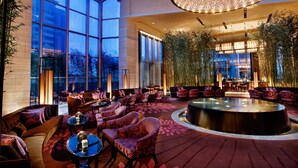 A spacious lobby with a high ceiling, large windows, and a central seating area with round tables and chairs. - Mels Weldon Dongguan Humen (Dongguan)