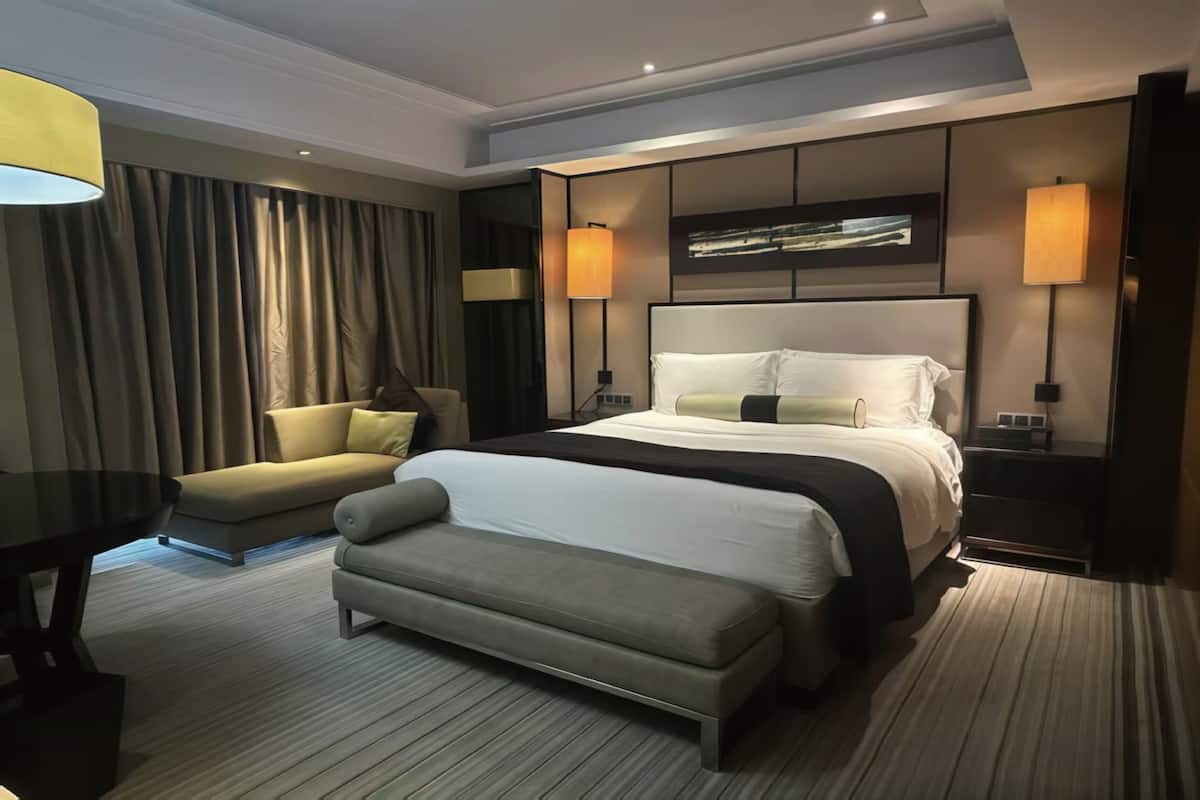 Une chambre d’hôtel moderne équipée d’un grand lit, d’un canapé, d’une banquette et d’une table à manger.