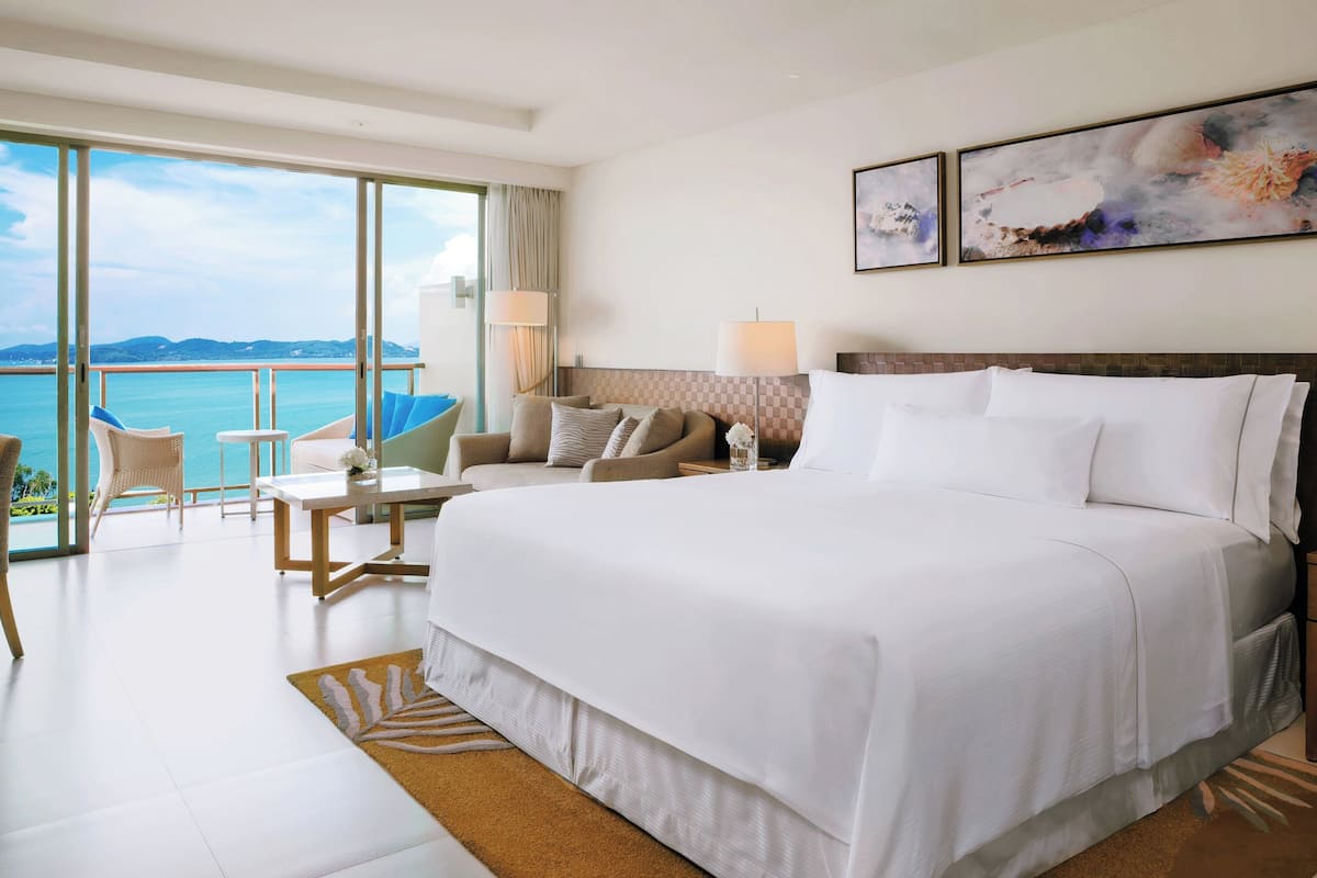 Une chambre d’hôtel avec un grand lit, un bureau, une chaise et une vue sur la mer.