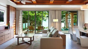 A modern living room with a sofa, coffee table, and dining area. There is a TV mounted on the wall and a ceiling fan.