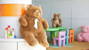 Children can play and explore in this child-friendly space with a large teddy bear, wooden blocks, and a small castle.