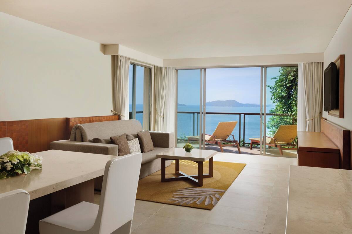Une chambre d’hôtel moderne dotée d’un balcon, d’un canapé, d’une table à manger et d’un téléviseur.