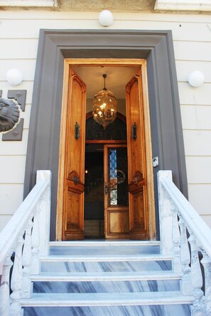A grand entrance with a wooden door, a chandelier, and marble steps. - Casa Del Trigo (Santa Fe)