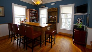 Eine Bar mit Holzhockern, einer Theke und einem Getränkeschrank.