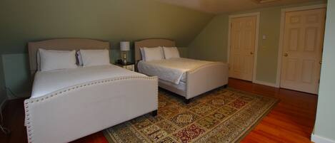 A bedroom with two beds, a patterned rug, and a ceiling light fixture.