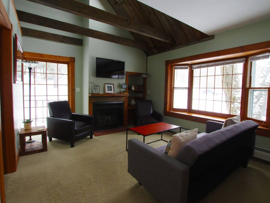 A cozy living room with a fireplace, comfortable seating, and large windows.