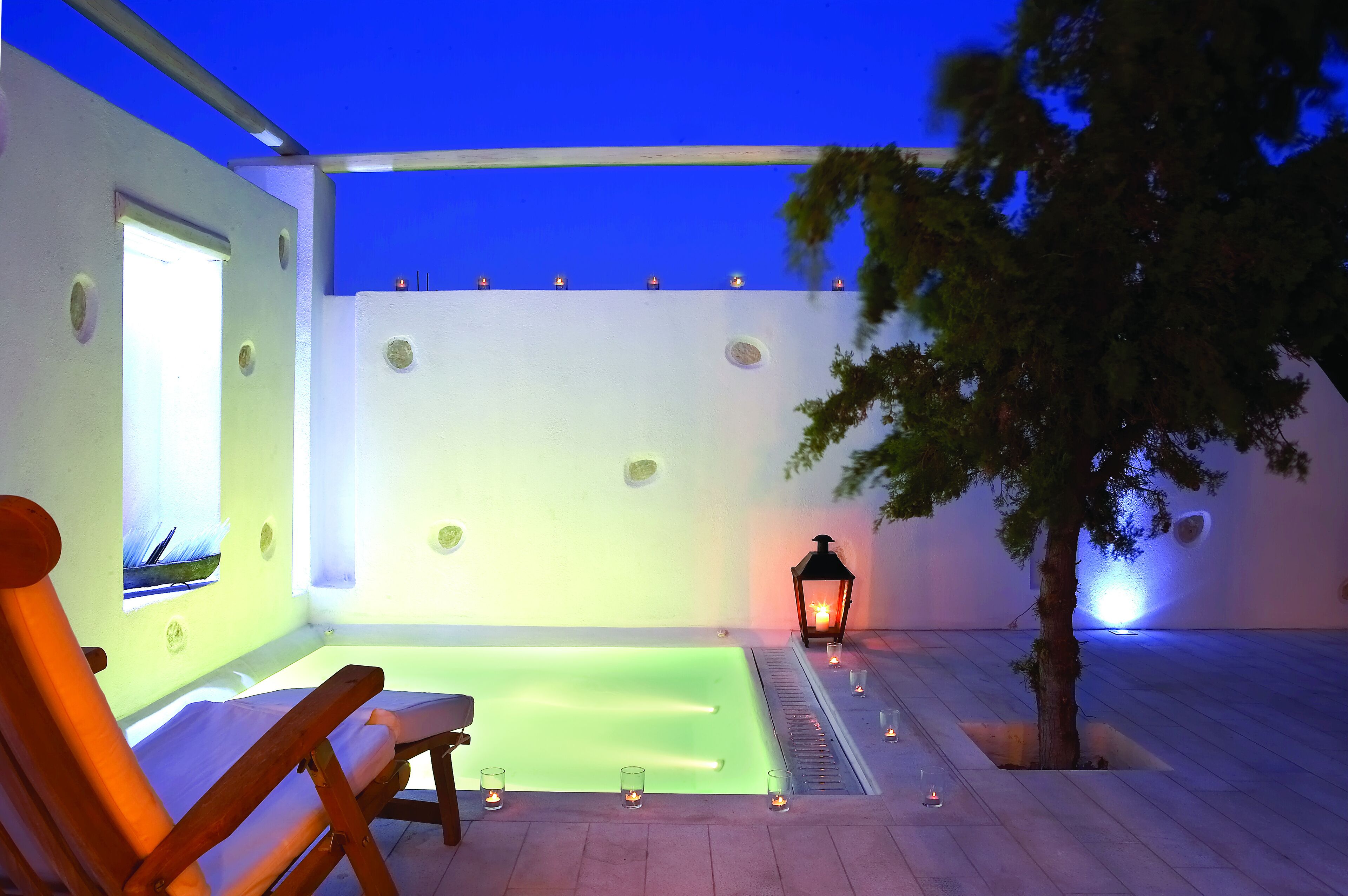 A spa area with a pool, a wooden chair, and a lantern.