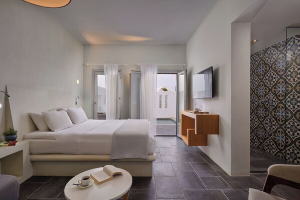 Ein modernes Hotelzimmer mit Bett, Schreibtisch, Fernseher und Blick ins Freie.