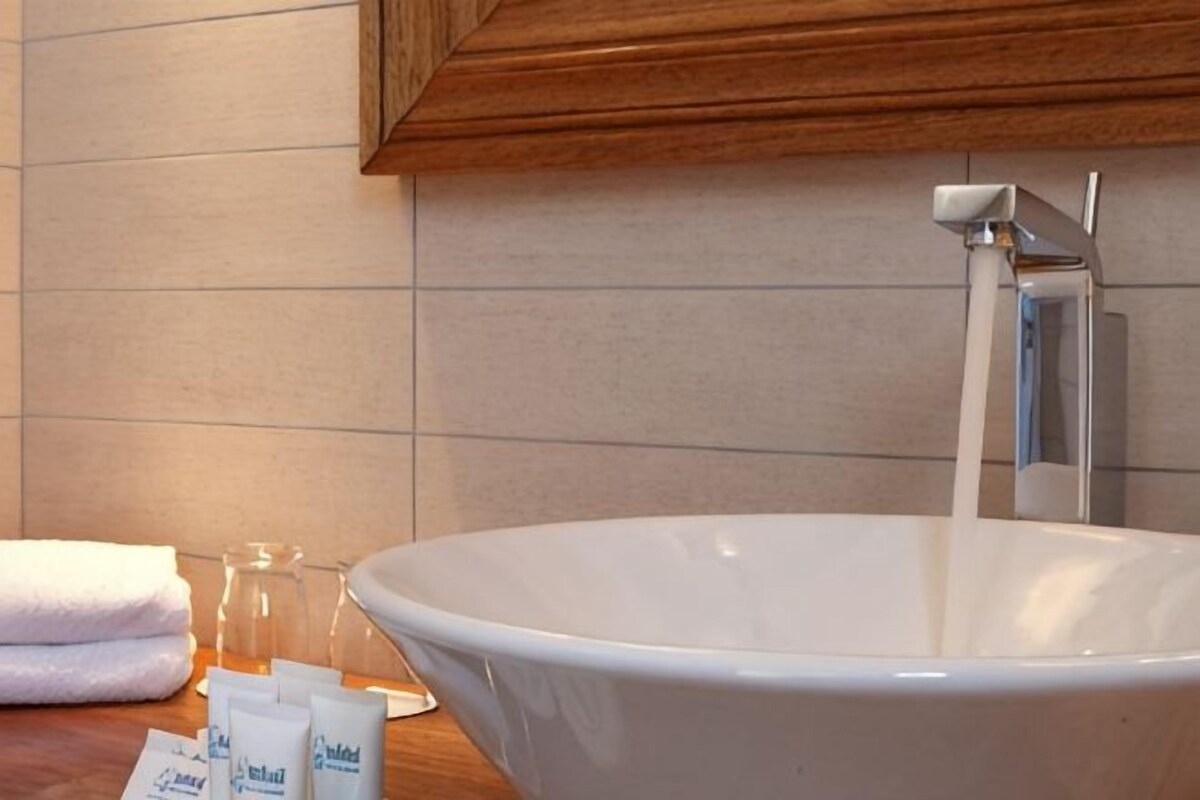 Un baño con un lavamanos blanco grande, una toalla y artículos de aseo en la encimera.