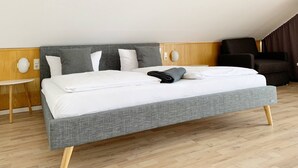A modern hotel room with a large bed, a small round table, and a dark armchair. - Parkhotel Cham (Cham)