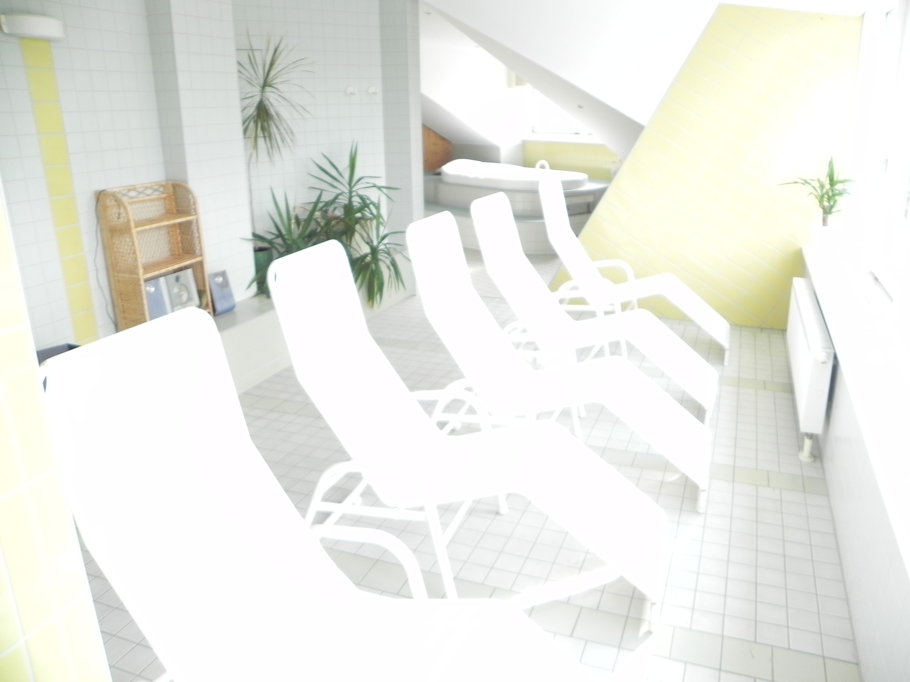 Un espacio interior moderno con sillones blancos y una pared amarilla.