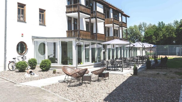 A building with a balcony, outdoor seating, and a bicycle. - Parkhotel Cham (Cham)