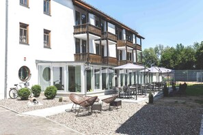 A building with a balcony, outdoor seating, and a bicycle. - Parkhotel Cham (Cham)