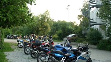 A row of parked motorcycles near a building with a spiral staircase.