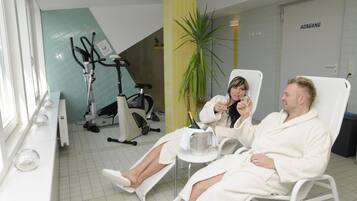 Une salle de spa équipée de deux fauteuils inclinables, d’un fauteuil de massage et d’une grande plante en pot.