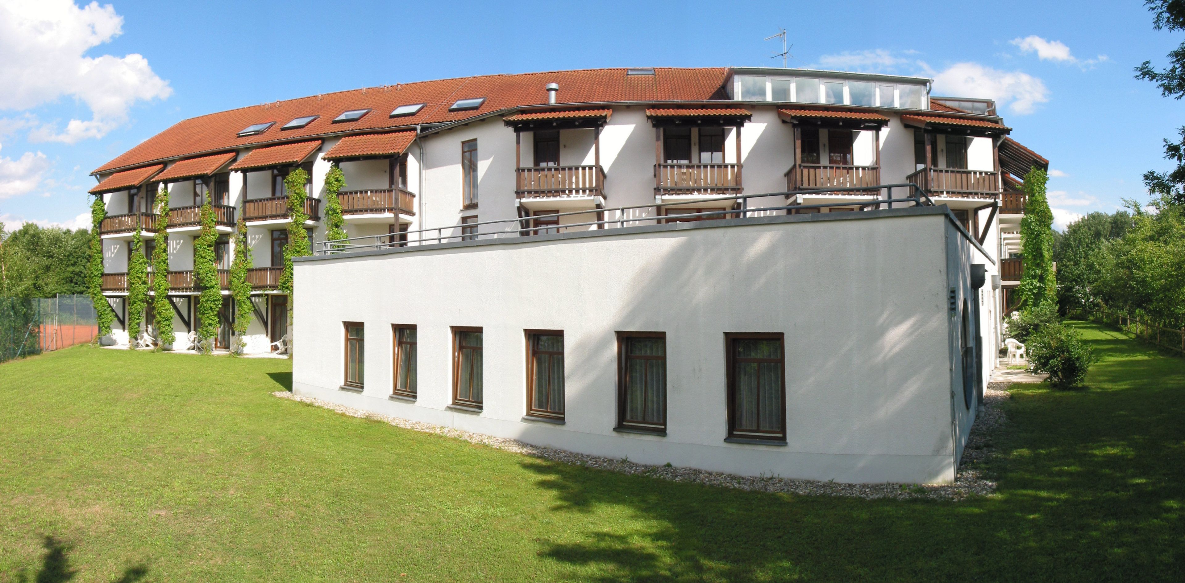 A two-story building with a red-tiled roof, multiple balconies, and a white facade.