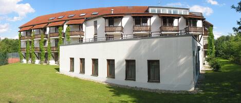 A two-story building with a red-tiled roof, multiple balconies, and a white facade.
