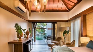 A modern hotel room with a wooden ceiling, a bed, a desk, and a seating area with chairs and a table. - Serrambi Resort (Ipojuca)