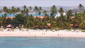 A beach resort with palm trees, beach umbrellas, and a clear view of the ocean. - Serrambi Resort (Ipojuca)