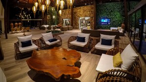 A spacious indoor lounge with wicker furniture, a large wooden coffee table, and hanging light fixtures. - Serrambi Resort (Ipojuca)