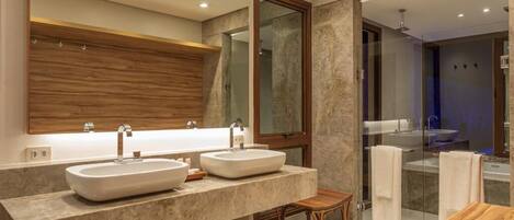 A modern bathroom with two sinks, a wooden vanity, and a glass shower enclosure.