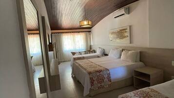 Habitación de hotel con dos camas, un espejo grande, un ventilador de techo y vista hacia otra habitación.
